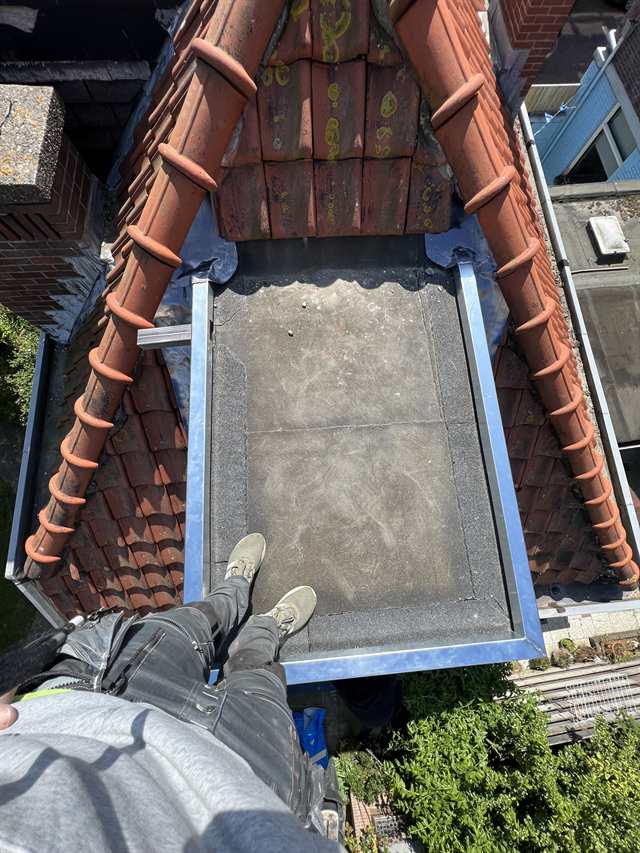 Plat dakje van een dakkapel met nieuwe dakbedekking en zinken randen, in een pannendak